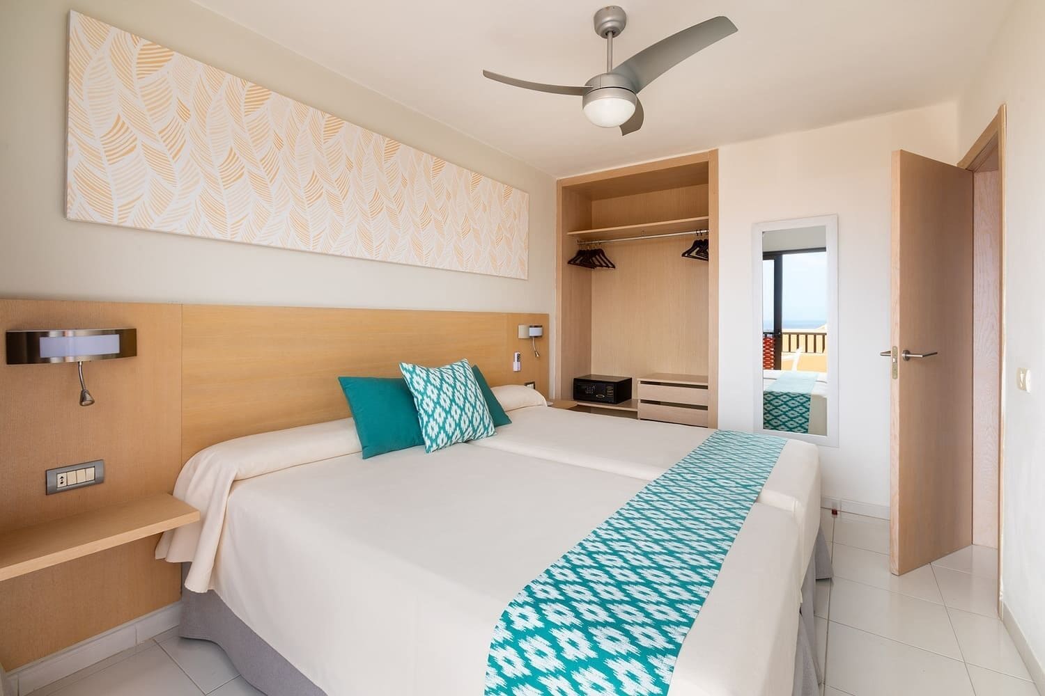 Une chambre d’hôtel comprenant un lit, un ventilateur de plafond, une table de chevet, une commode, une armoire et une vue sur l’extérieur.