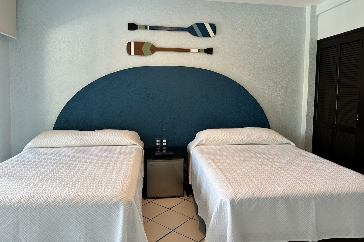 A hotel room with a large bed, two bedside tables, a small desk, and a wall-mounted TV.