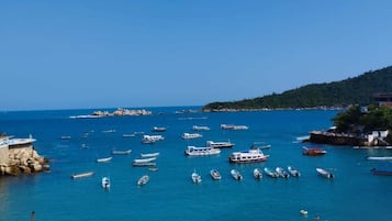 Vista costera con barcos, una playa de arena y terreno rocoso.
