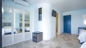 A hotel room with a bed, a small desk, a TV, and a door.