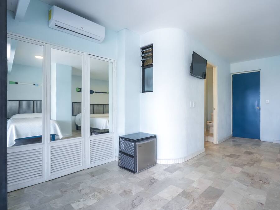A hotel room with a bed, a small desk, a TV, and a door.