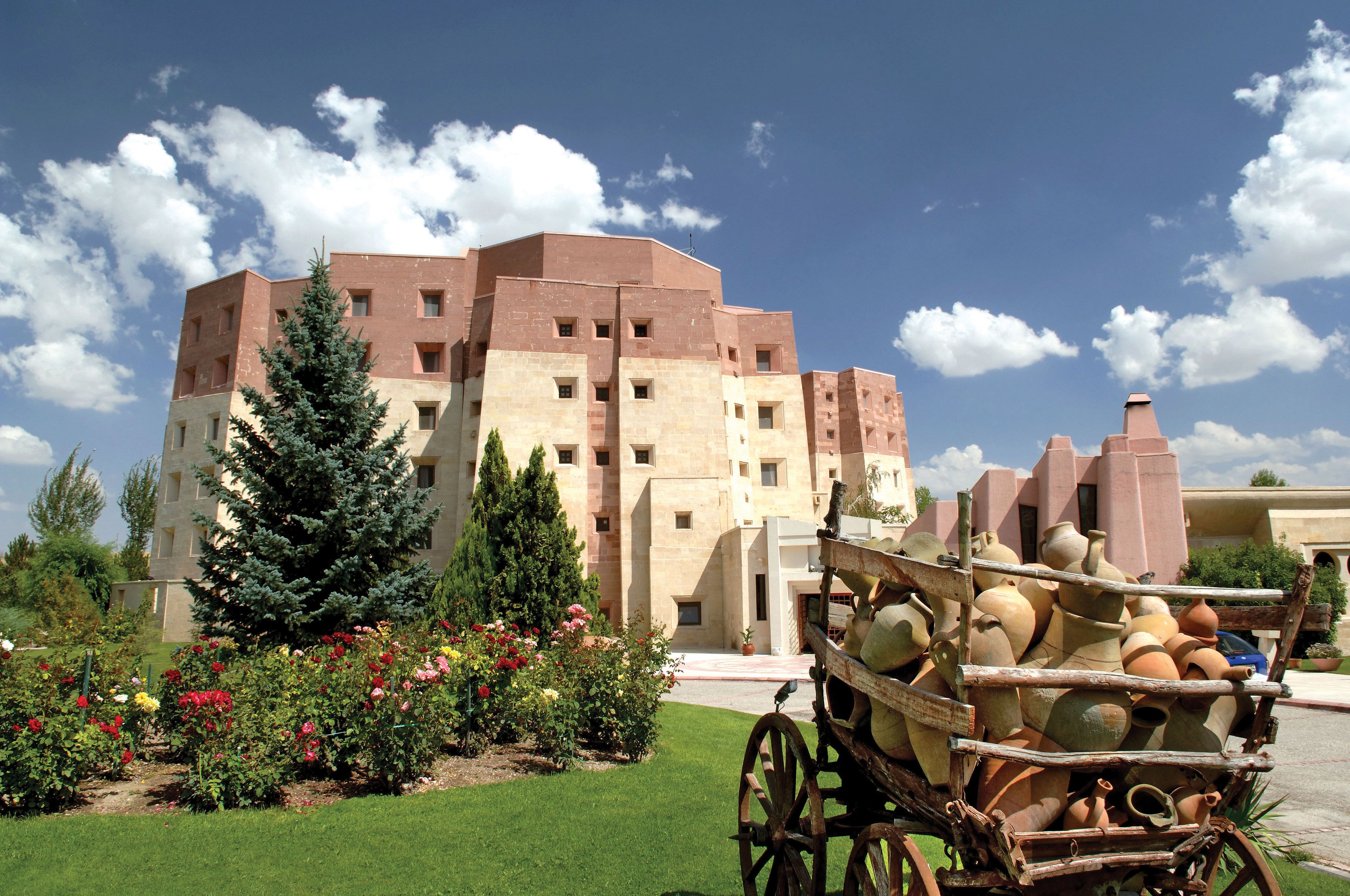 A building with a courtyard, a wooden cart with pottery, and a variety of flowers.
