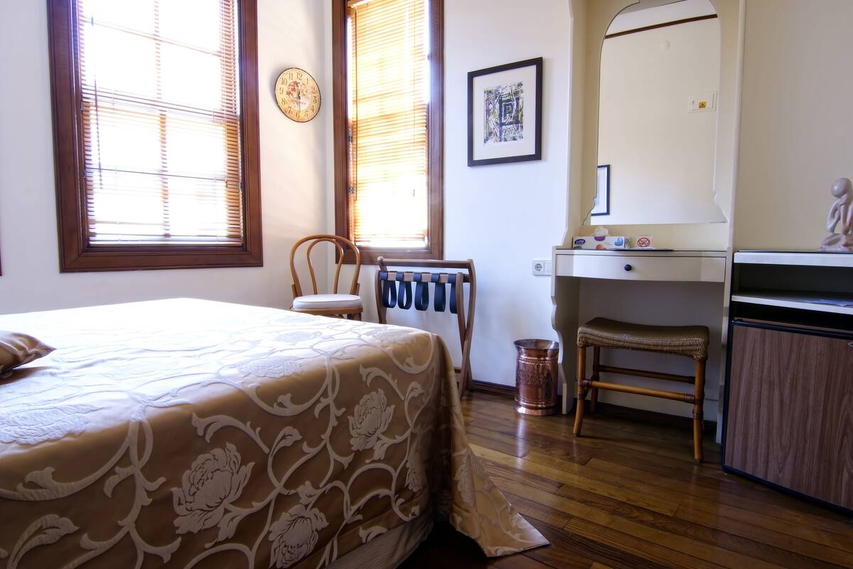 A bedroom with a bed, a chair, a desk, and a radiator.