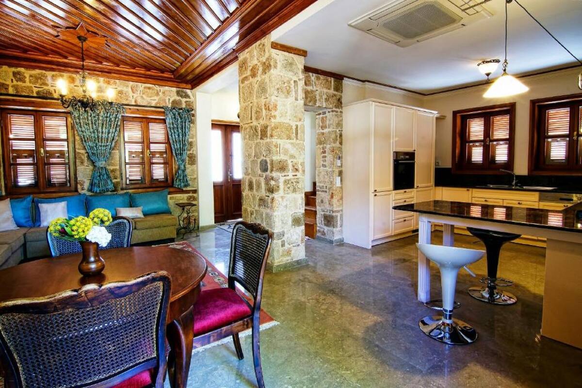 A spacious living area with a stone wall, wooden ceiling, and a dining table with chairs.