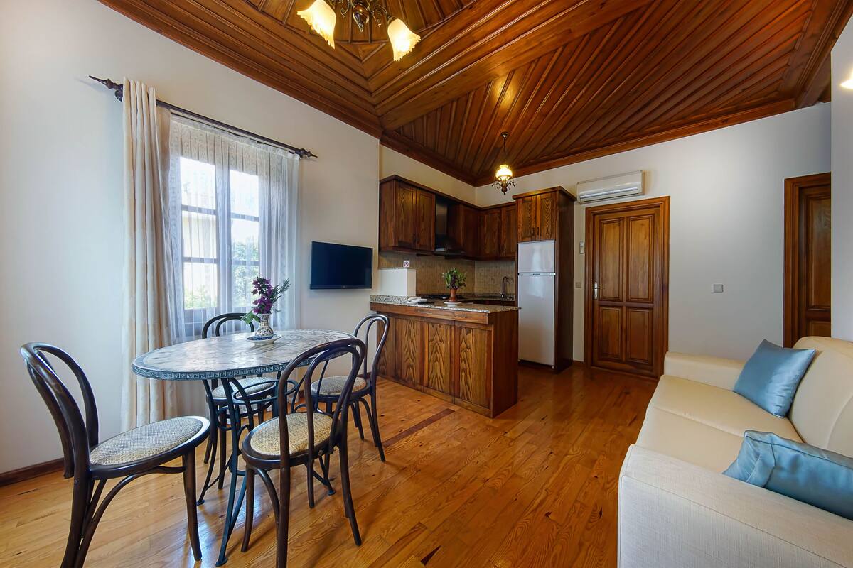 A cozy kitchen with wooden cabinets, a dining table with chairs, and a built-in oven.
