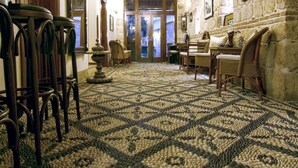 A hallway with a patterned carpet, wooden furniture, stone walls, and a chandelier. - Minyon Hotel (Antalya)