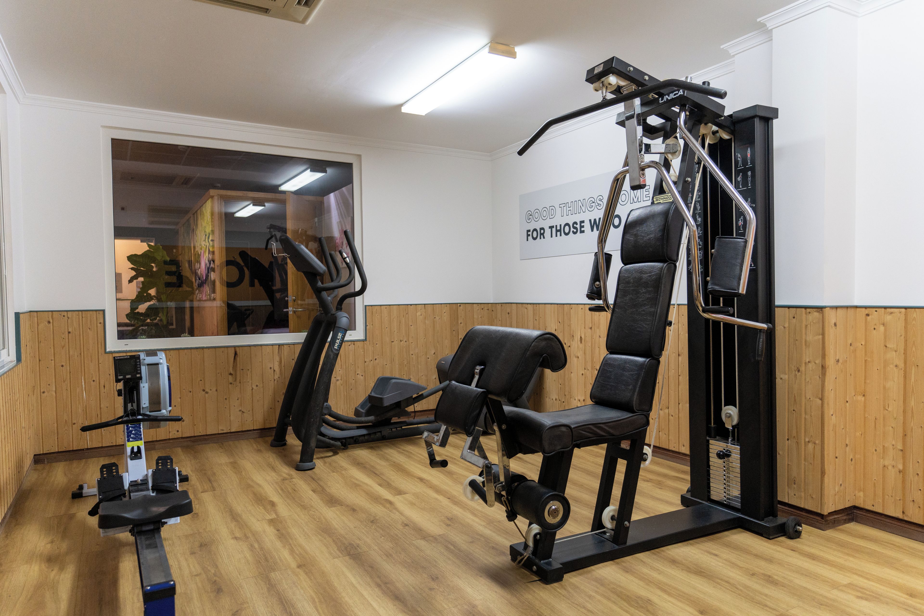 A gym with exercise equipment, a wall-mounted sign, and a window with a view.