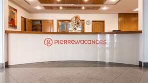 Uma mesa de recepção com um logotipo, um relógio e um arranjo de flores.