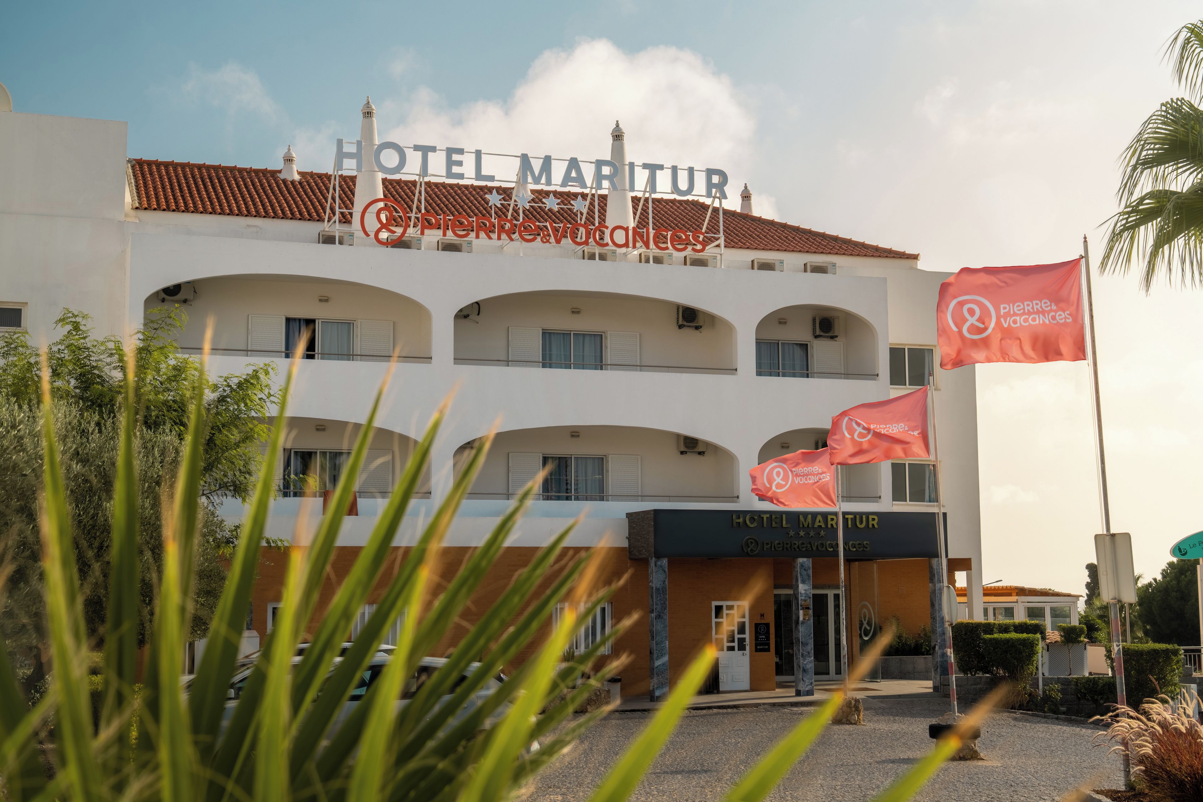 A hotel with a sign reading 'HOTEL MARITUR & PIERRE&VACANCES' and multiple flags.