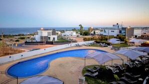 A pool area with lounge chairs and umbrellas, a clear view of the ocean, and modern buildings in the background. - Hotel Maritur - Adults Only by Pierre & Vacances (Albufeira)