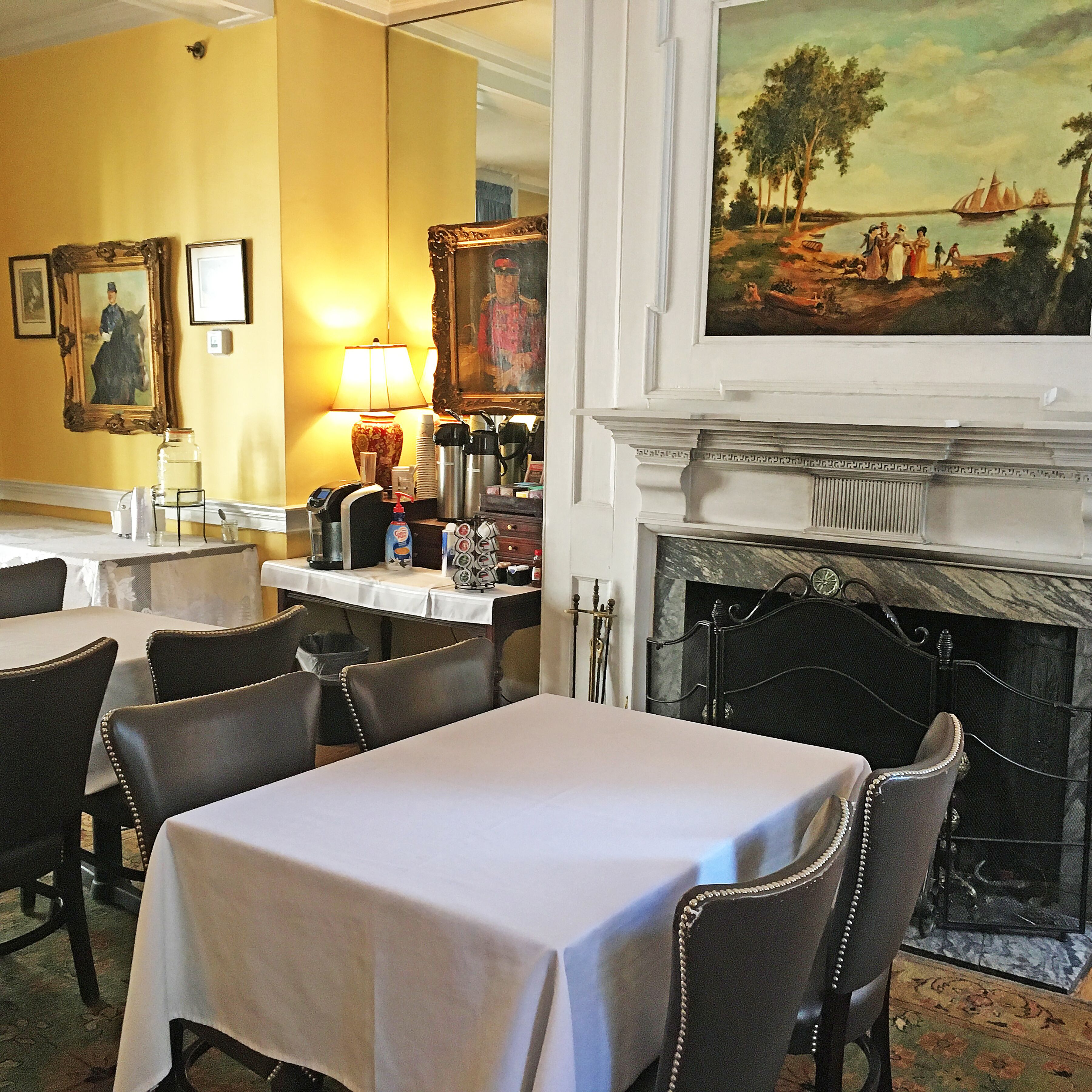 Un espace repas comprenant des tables, des chaises, une cheminée et des tableaux aux murs.