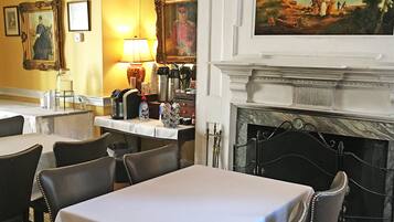 Un espace repas comprenant des tables, des chaises, une cheminée et des tableaux aux murs.