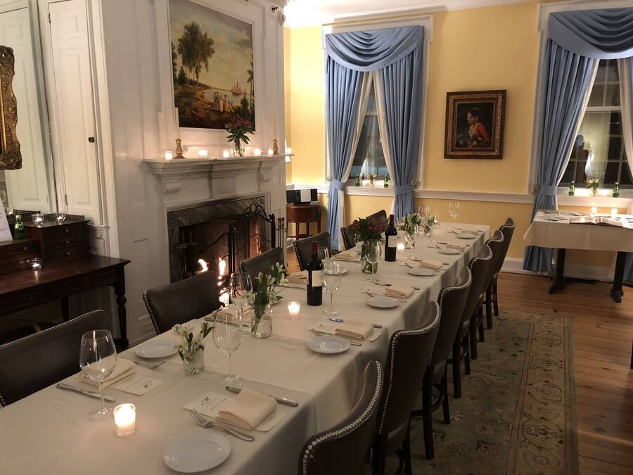 A formal dining room with a long table set for a meal, a fireplace, and a painting on the wall.