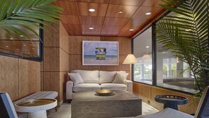 Un área de estar moderna con techo de madera, un sofá color beige, una mesa de centro y vistas al exterior.