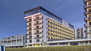 Un hotel de varios pisos con un diseño moderno, con balcones en cada planta y un letrero destacado que dice "HENLOREN HOTEL".