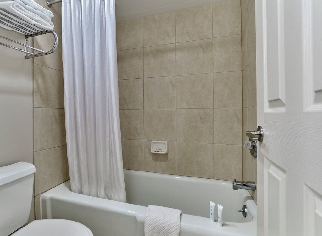 A bathroom with a bathtub, toilet, and a towel rack.