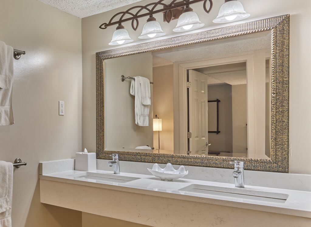 A bathroom with a large mirror, two sinks, and a towel rack.
