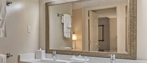 A bathroom with a large mirror, two sinks, and a towel rack.