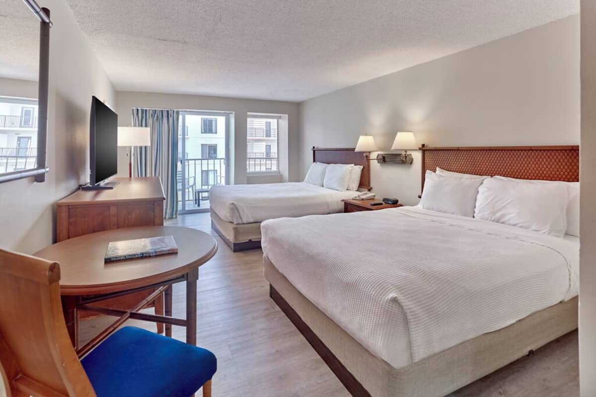 Una habitación de hotel con dos camas, un escritorio, una silla y un televisor.