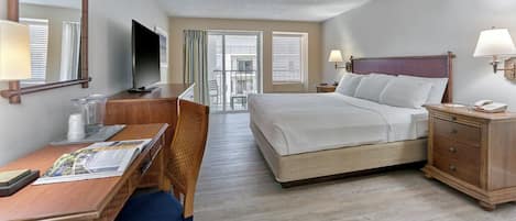 A hotel room with a bed, desk, chair, TV, and a view of the outside.