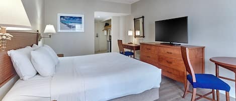 Une chambre d’hôtel avec un grand lit, un bureau avec une télévision, une chaise et une lampe.
