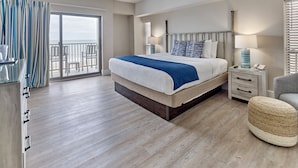 Habitación de hotel moderna con una cama grande, un balcón, un escritorio y una silla.