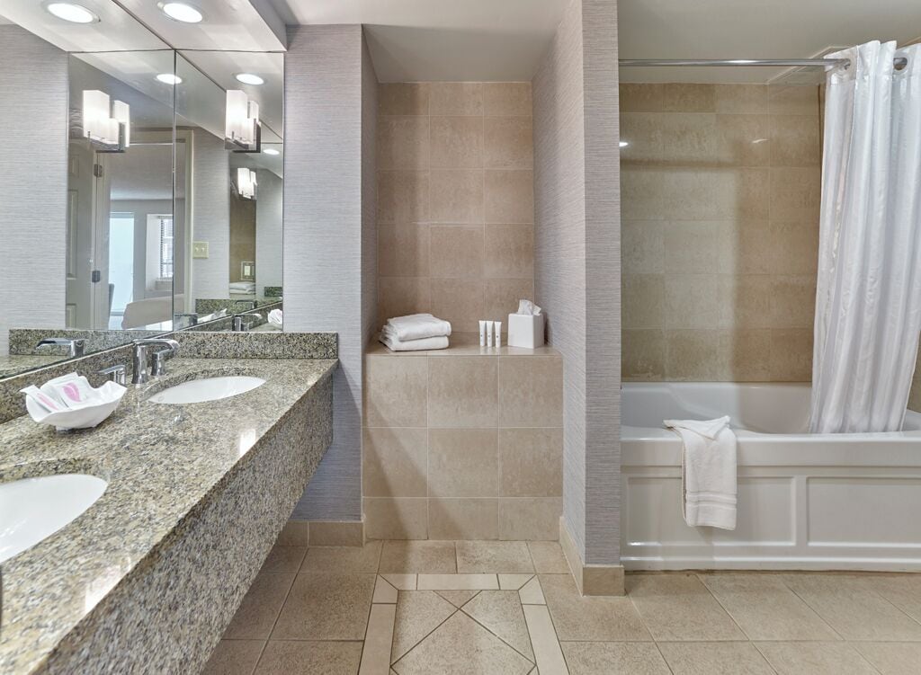 A modern bathroom with two sinks, a shower, and a bathtub.