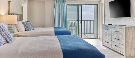 Habitación de hotel con dos camas, televisión, balcón y vistas, además de un aparador.