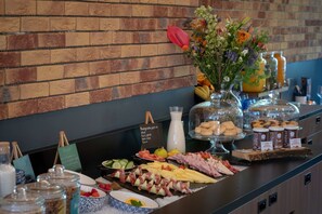 A buffet with various food items, a brick wall, and a vase of flowers.