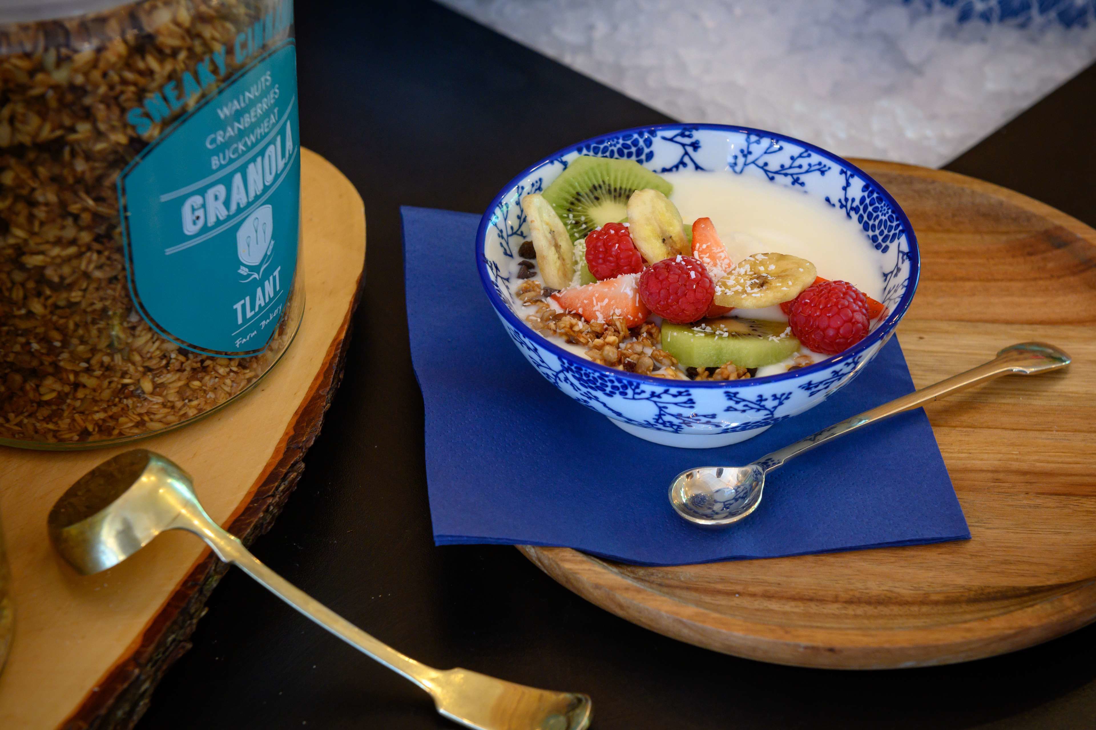 Un tazón de granola con frutas y una cuchara sobre una tabla de madera.