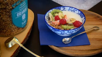 Un tazón de granola con frutas y una cuchara sobre una tabla de madera.