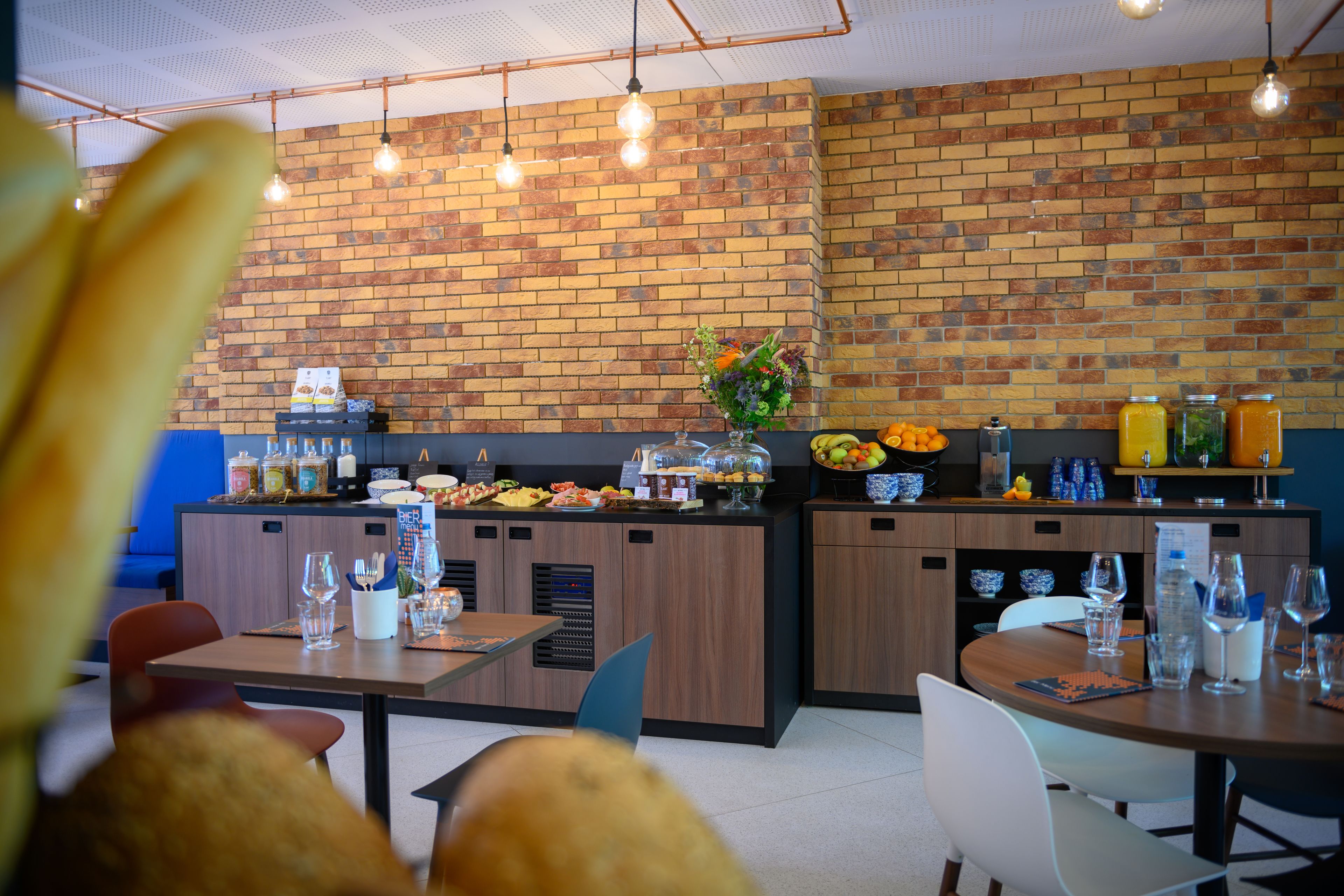 Un restaurante con pared de ladrillo, mostrador de madera y luces colgantes.