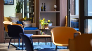 A modern living room with a sofa, chairs, a coffee table, and a bookshelf. - Tulip Inn Antwerpen (Antwerp)
