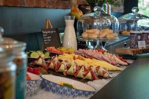 A buffet with various cheeses, meats, and fruits.