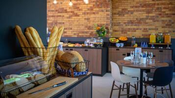 A cafรฉ with a brick wall, a counter with bread, and a dining area with chairs and tables.