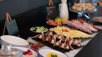 A buffet with various food items including cheese, meats, and fruits, with a sign indicating allergy information.