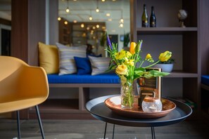 A modern living room with a round table, a yellow chair, and a blue sofa with striped cushions. - Tulip Inn Antwerpen (Antwerp)
