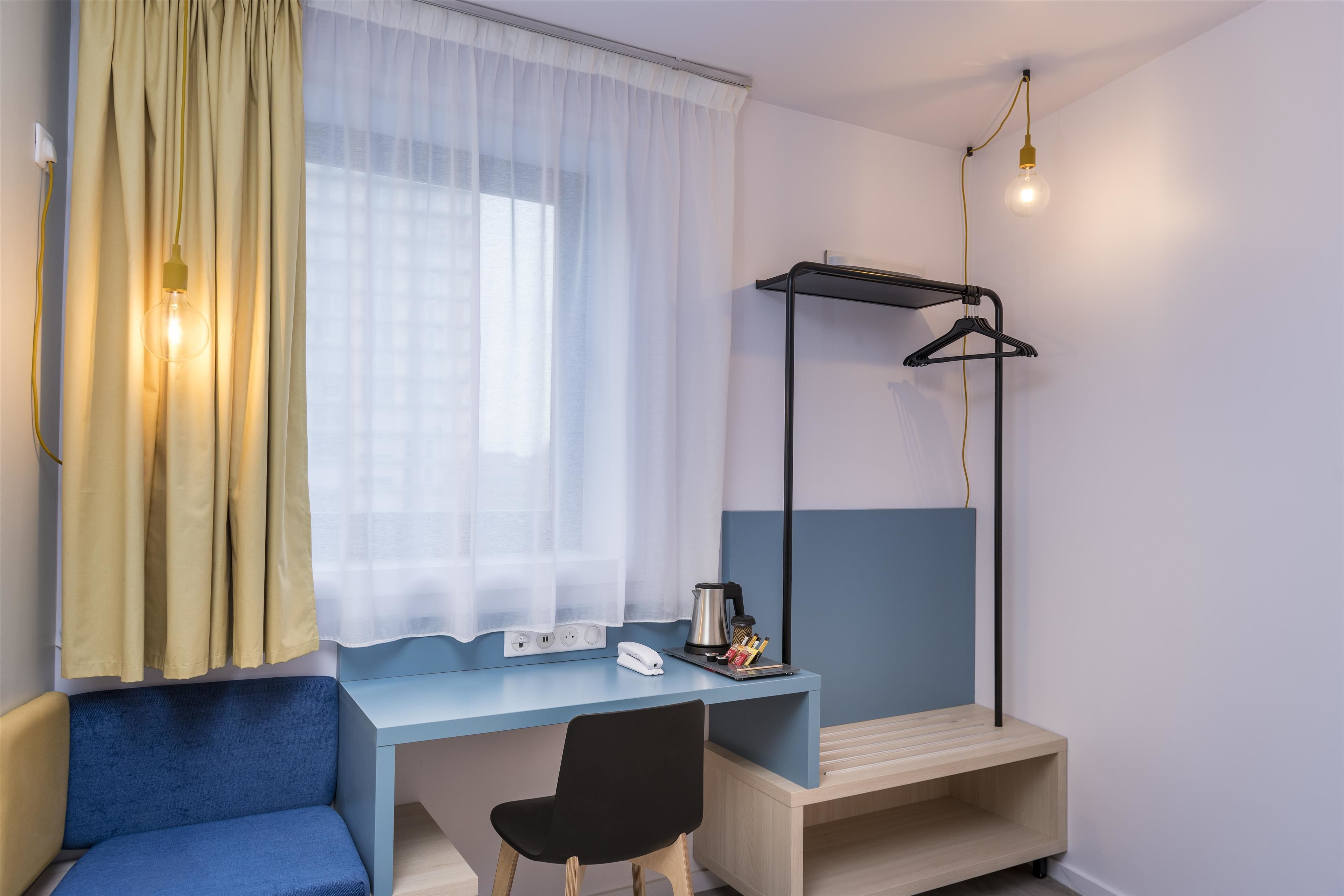 Una habitación pequeña con escritorio, silla y lámpara colgante.