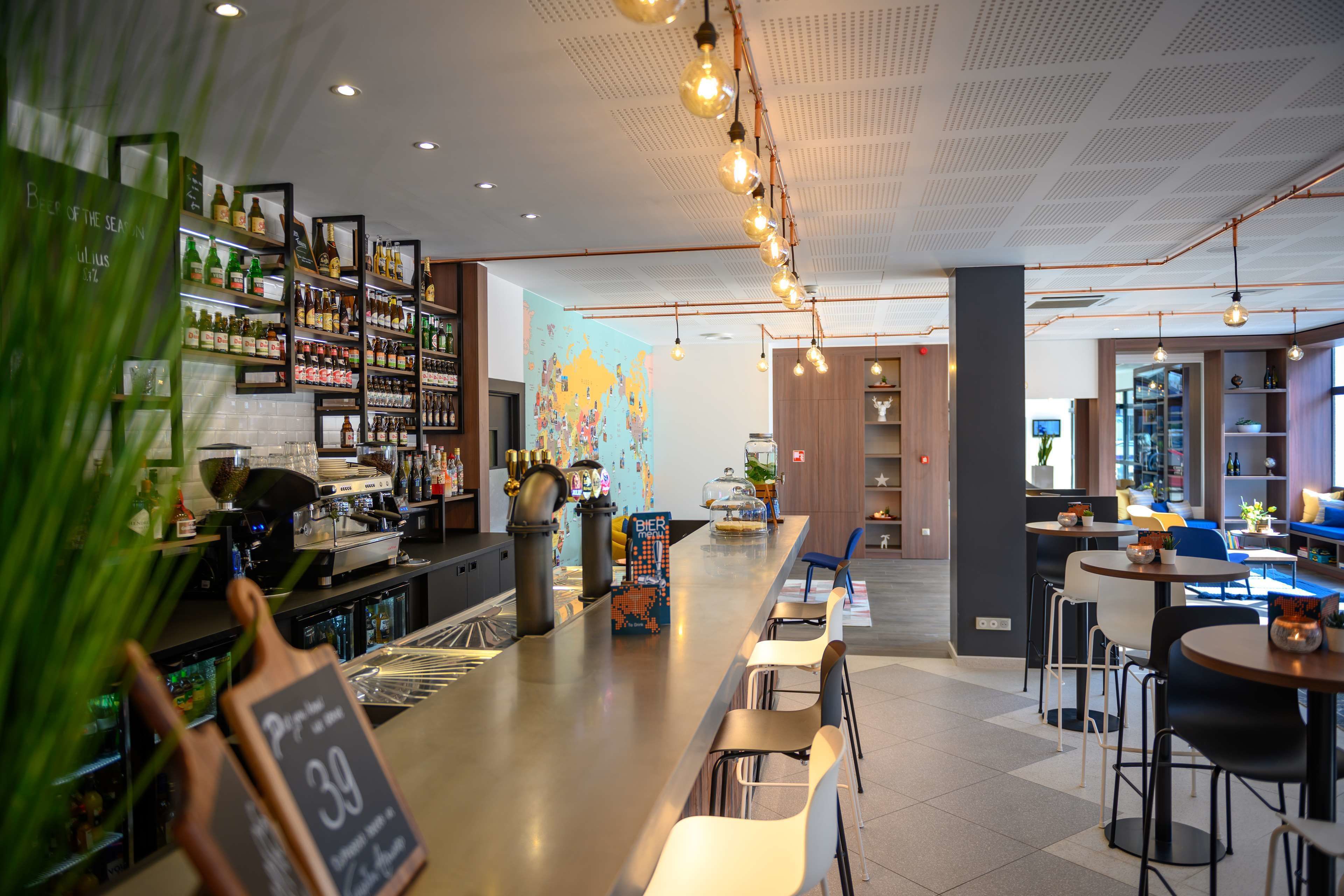 Et moderne barområde med en lang bar, hylder med flasker og et verdenskort på væggen.