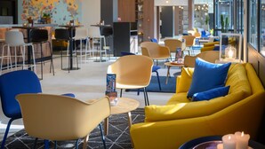 A modern interior with yellow sofas, blue chairs, and a bar area. - Tulip Inn Antwerpen (Antwerp)