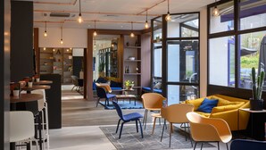 A modern interior with a dining area, seating, and large windows. - Tulip Inn Antwerpen (Antwerp)