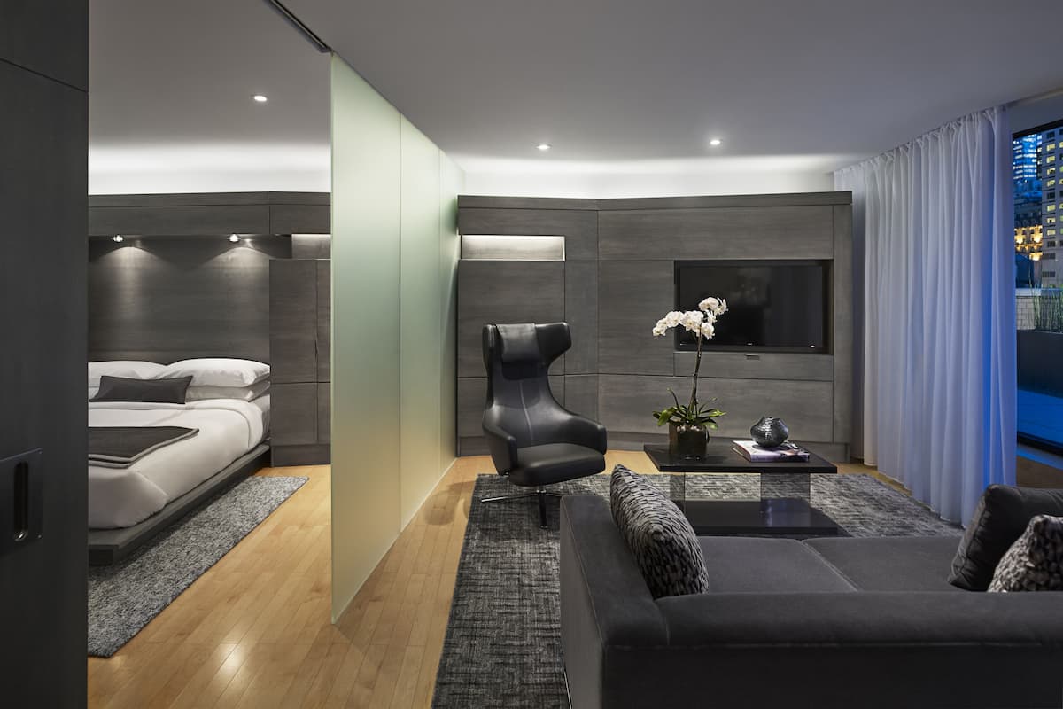 A modern living room with a sofa, a chair, a coffee table, and a TV mounted on the wall.
