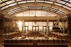 A spacious indoor dining area with high ceilings, large windows, and string lights. - Chicago Athletic Association, a Hyatt Hotel (Chicago)