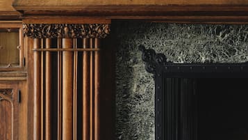 A fireplace with a fire, flanked by wooden columns and a marble floor.