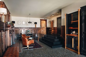 A spacious living area with a staircase, a dining area, and a library.