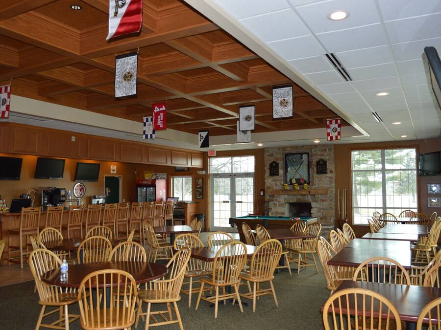 A spacious indoor dining area with wooden tables and chairs, a bar area, and a stone fireplace.