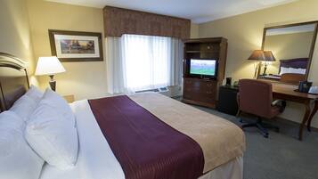 A hotel room with a bed, a desk, a chair, a television, and a mirror.