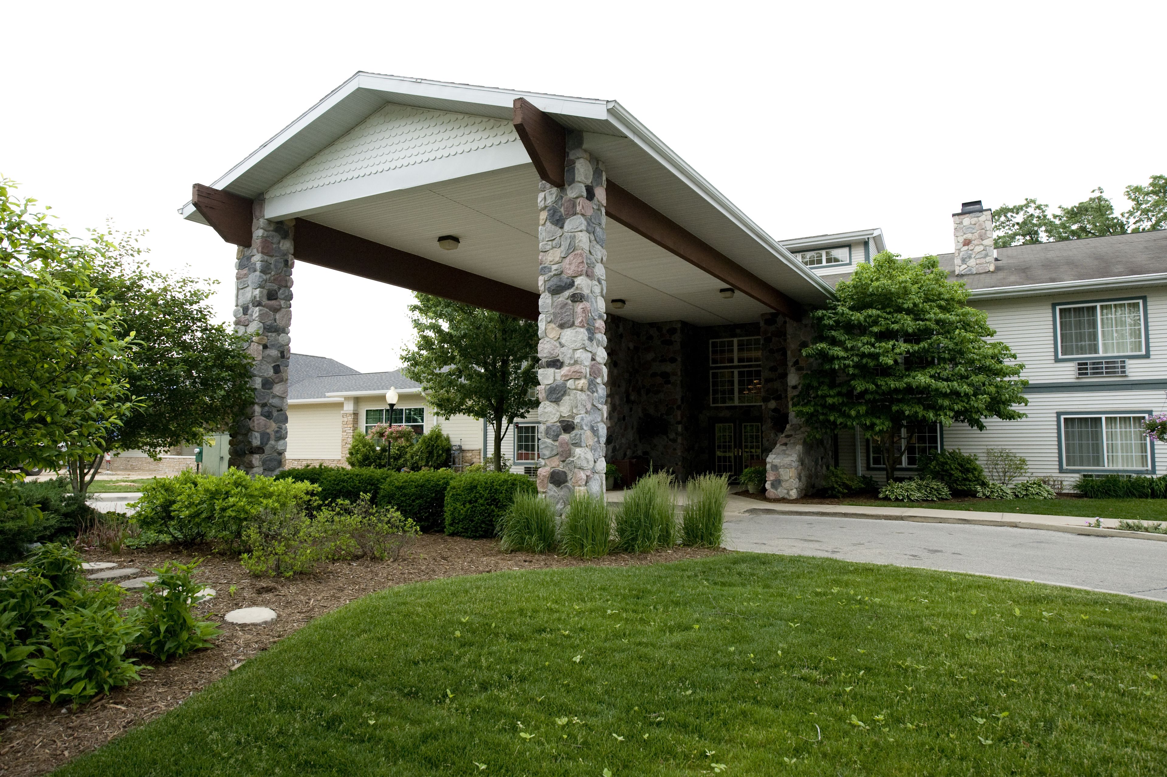 A house with a stone pillar porch, a covered entryway, and a well-maintained lawn.