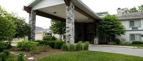 A house with a stone pillar porch, a covered entryway, and a well-maintained lawn.