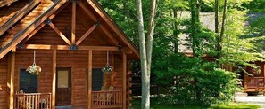 Une cabane en bois avec une véranda, un luminaire suspendu et une fenêtre.